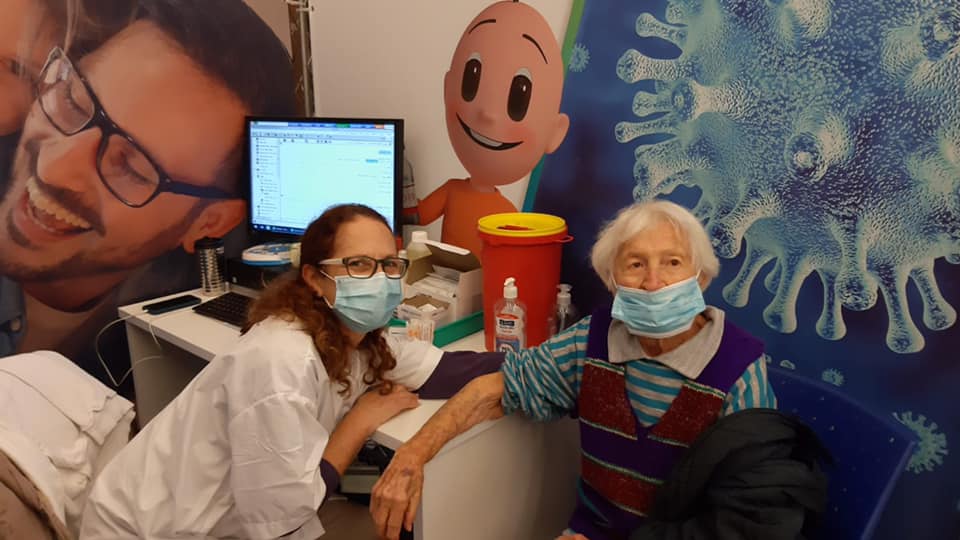 מרים גוטמן בת 104 מנען מקבלת את החיסון על ידי נכדתה, איריס בן-ארי