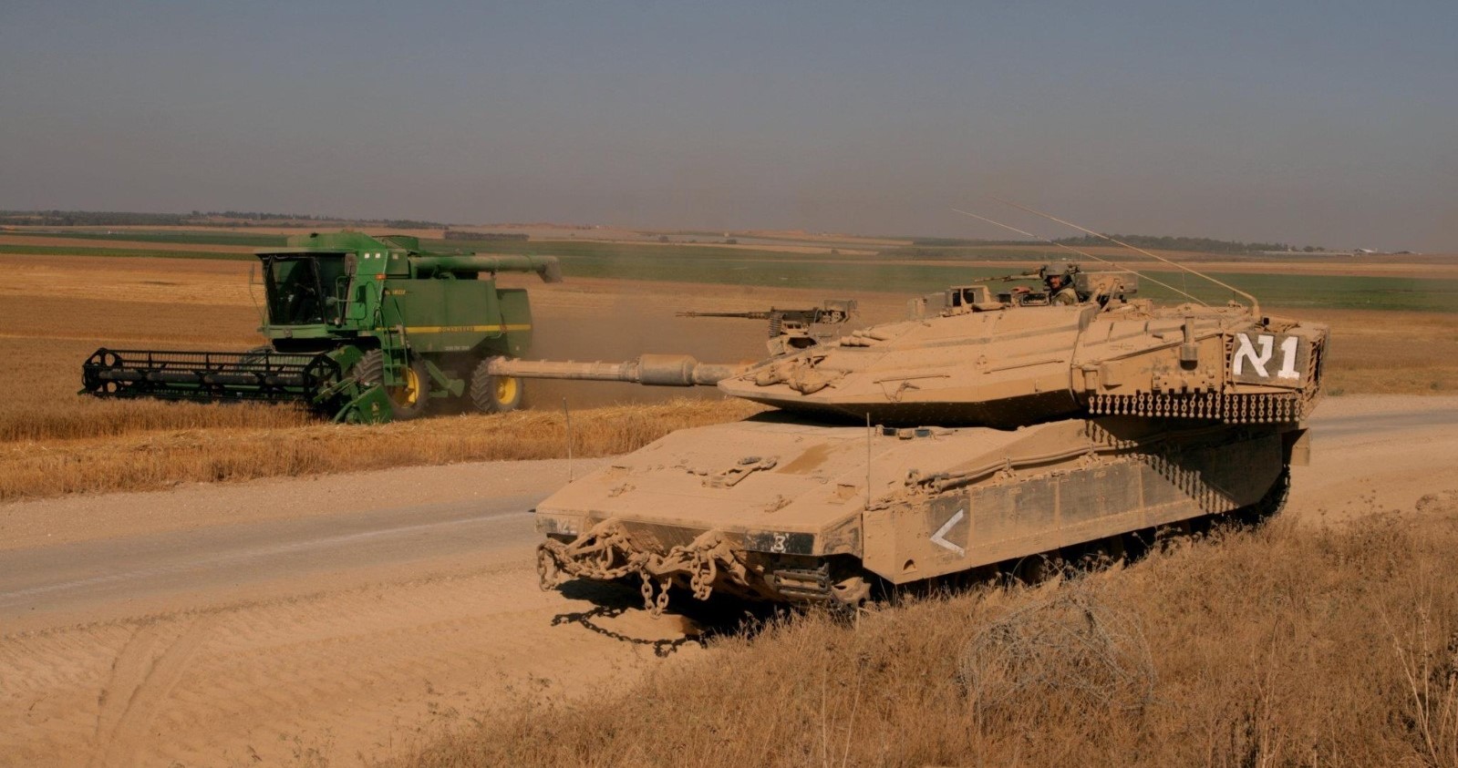טנק שומר על קומביין שקוצר בשדות עוטף עזה במהלך מבצע צוק איתן. צילום: רפי בביאן