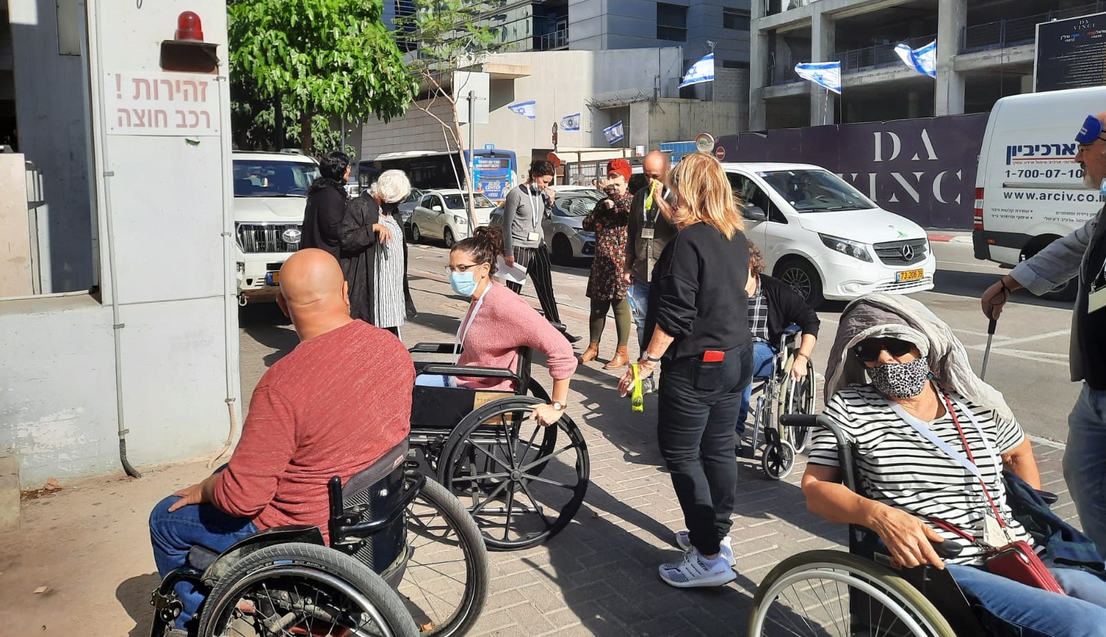 משתתפות ומשתתפי הקורס מתנסים בהתניידות בכיסא גלגלים וללא יכולת לראות בסמוך לבית התנועה